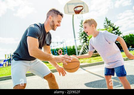 Happy Basketball Familie Porträt spielen diesen Sport in der Sommersaison. Der Vater spielt mit dem Jungen Stockfoto