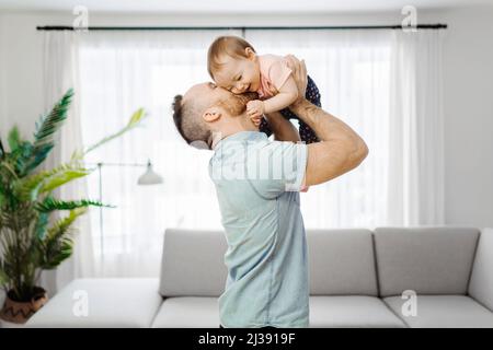 Vater mit seiner kleinen Tochter, die im Wohnzimmer lustig war Stockfoto