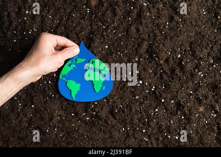 Papier Schnitt Wassertropfen mit Weltkarte innen von Hand auf natürlichen Boden Hintergrund gehalten. Speicherplatz kopieren. Stockfoto