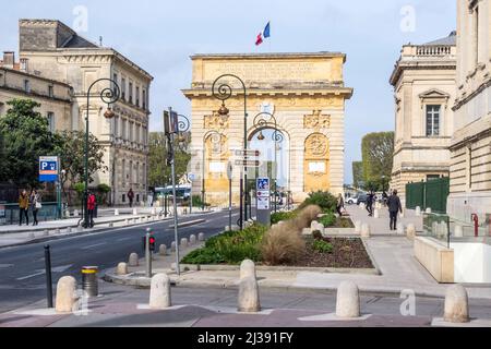 MONTPELLIER, FRANKREICH - 31. MÄRZ 2017: Arc de Triumph in Montpellier, aus dem Jahr 1692, mit umliegenden Gebäuden, Menschen und Verkehrsschildern. Stockfoto