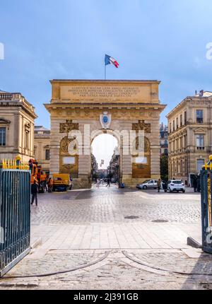 MONTPELLIER, FRANKREICH - 31. MÄRZ 2017: Arc de Triumph in Montpellier, aus dem Jahr 1692, mit umliegenden Gebäuden, Menschen und Verkehrsschildern. Stockfoto