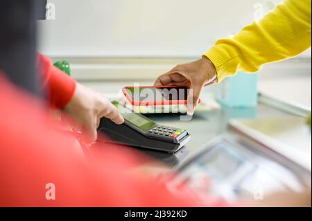 Crop anonyme Person in gelben Pullover mit Handy, während am Tisch mit Kreditkarte sitzen Stockfoto