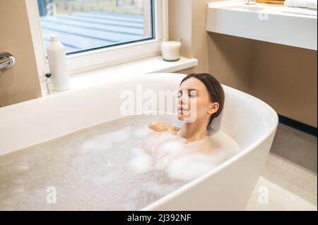 Hübsche Dame, die zu Hause ein entspannendes Bad nimmt Stockfoto