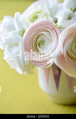 Nahaufnahme von weißen und rosafarbenen Frühlingsblumen in einer Vase vor gelbem Hintergrund. Schöner Tischbukett. Stockfoto