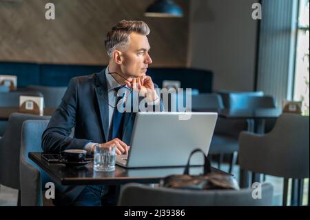 Ein Geschäftsmann mittleren Alters, der am Laptop sitzt und nachdenkt Stockfoto