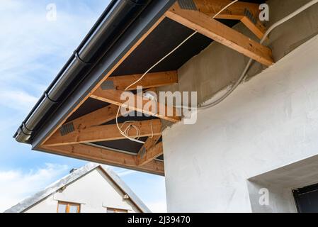 Steckdose an den Traversen über dem Garagentor montiert, Elektrokabel in pvc-Rohr. Stockfoto