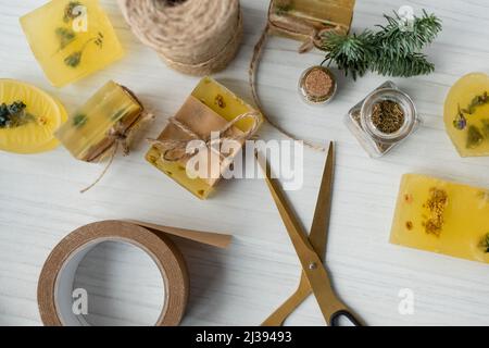 Draufsicht auf handgeklebte Seifenstücke in der Nähe von Klebeband und Schere auf dem Tisch Stockfoto