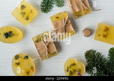 Draufsicht auf handgemachte Seifenstücke in der Nähe von Kiefernästen auf dem Tisch Stockfoto