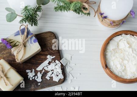 Draufsicht auf handgemachte Seife in der Nähe von Flocken und Kerzen auf dem Tisch Stockfoto