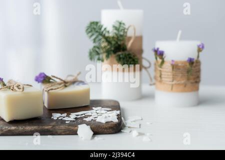 Bastelseife auf Schneidebrett in der Nähe verschwommener Kerzen auf dem Tisch Stockfoto