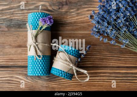 Draufsicht auf handgefertigte Kerzen und Lavendelblüten auf Holzoberfläche Stockfoto