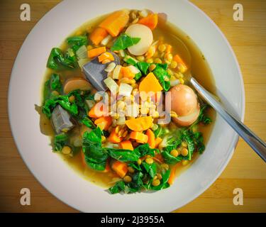 Eine Schüssel Gemüselensuppe, eine vegane Mahlzeit, von oben gesehen in der Landküche Stockfoto