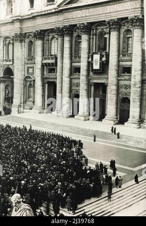 Die Bekanntgabe des Namens des neuen Papstes -- die Szene als Kardinal dominoni verkündete den Namen des neuen Papstes vom Balkon des heiligen Petrus an die Menge unten. Laute Lautsprecher hallten die Ansage überall auf dem Platz. Nach der dritten Wahl der Kardinäle März 2. Das weiße Rauchsignal deutete der riesigen Menschenmenge, die sich auf dem Petersplatz in Rom versammelt hatte, an, dass ein neuer Papst gewählt worden war. Einige Zeit später erschien Kardinaldiakon Caccia Dominoni auf dem Balkon von St. Peter und verkündete, dass Kardinal Pacelli die notwendige Zweidrittelmehrheit von den Kardinälen erhalten hatte, wodurch er die Wahl hatte Stockfoto