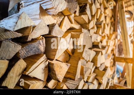 Gehacktes und gehacktes Brennholz gestapelt und für den Winter in einem Brennholzschuppen geerntet. Lagerung von Brennholz im Sommer Stockfoto