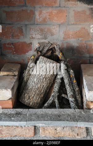 Vintage Kamin mit gehacktem Holz und Ziegelwänden. Stücke aus Hartholz, die als Brennholz im Gebäude verwendet werden können Stockfoto