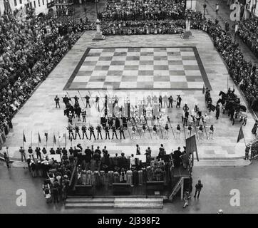 Living Chess -- in gepanzerten Kostümen des Mittelalters stehen sich die beiden 'Rivalen Ritter' auf der Hauptplattform gegenüber, bereit, ein echtes Schachspiel zu spielen, von dem jede Bewegung auf dem riesigen Schachbrett gespielt wird. Kostümierte Mädels und Adlige sehen zu Beginn des Spiels an. Hinter dem Spieler auf der linken Seite verbirgt sich die schöne „Leonora“, die Tochter des Gouverneurs und der „Einsatz“ des Spiels. Das andere Mädchen, rechts, trägt Tiara, repräsentiert ihre Schwester. Laut der happy-end Medieval Legend, wurde sie als Trostpreis an den verlorenen Ritter verliehen. 23. September 1955. (Foto von United Press). Stockfoto