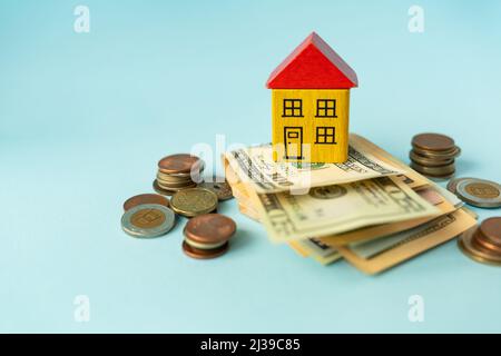 Geld in internationaler Währung, einschließlich Euro, Dollar, eine Münze, auf der sich ein Spielzeughaus befindet. Das Konzept der Hypotheken, Investitionen, Kredite, Schulden, ho Stockfoto