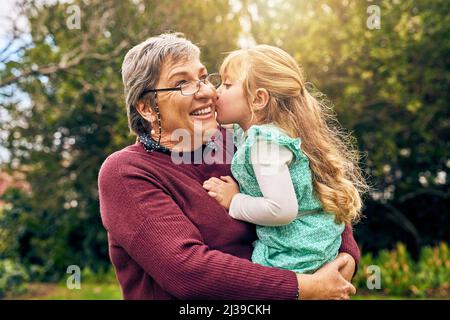 Du wirst immer Grannys kleines Mädchen sein. Schuss einer Enkelin, die draußen ihre Großmutter auf die Wange küsst. Stockfoto