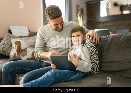 Vater oder Pate mit Basset Hund Spaß im Wohnzimmer zu Hause mit Computer-Tablet Stockfoto