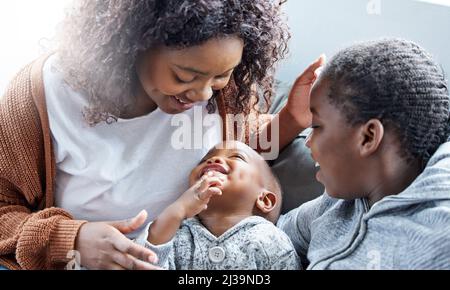 Es gibt nichts wie eine Mutterliebe. Aufnahme einer Mutter, die mit ihren Kindern auf der Couch in der Lounge zu Hause spielt. Stockfoto