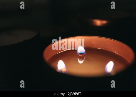 Kupferkerze mit drei Flammen und dunklem Hintergrund Stockfoto