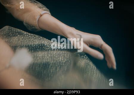 Hand mit Tattoo in glitzerndem Kleid schwimmend unter Wasser Stockfoto