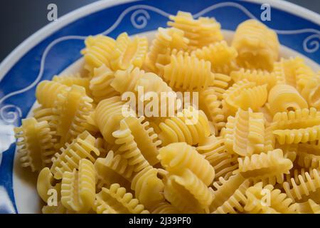 Nahaufnahme eines Tellers roher italienischer getrockneter Pasta, bekannt als radiatori Stockfoto