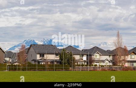 Wunderschöne frühmorgendliche Frühlingsansicht von Holzhäusern mit Bergen und Wolken im Hintergrund in Kanada. Straßenfoto, selektiver Fokus, Reisefotoaufnahme Stockfoto