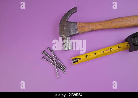 Flatlay von Hammer, Nageln und Band Maß isoliert auf einem Lavendel Purple Hintergrund Stockfoto