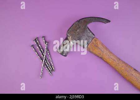 Flatlay Ansicht von Hammer und Nägel isoliert auf einem Lavendel lila Hintergrund Stockfoto