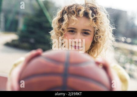 Hübsche junge kaukasische Frau, die einen Basketballball vor ihrem Nahaufnahme-Kopierraum hält. Hochwertige Fotos Stockfoto