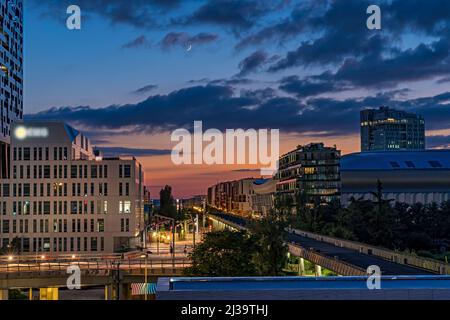 Mondsichel über dem La Defense District bei Sonnenuntergang in Paris Stockfoto