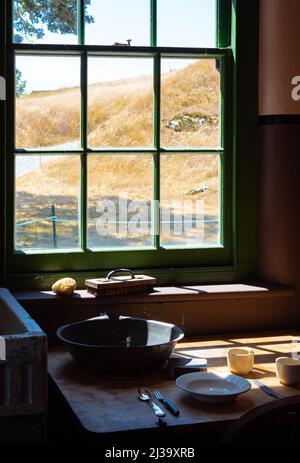 Alte Zeiten Bauernhaus Interieur eines alten Landhauses Küche. Ländliche Wohnküche mit abgenutztem Holztisch und Rührschüssel, Löffel, Teller. Selektiver Fokus Stockfoto