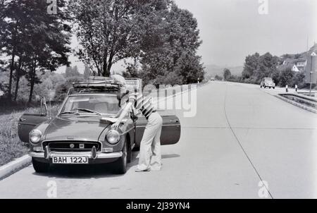 Vintage-Bild einer Frau beim Lesen der Karte auf der englischen Motorhaube in deutschland 1970 Stockfoto