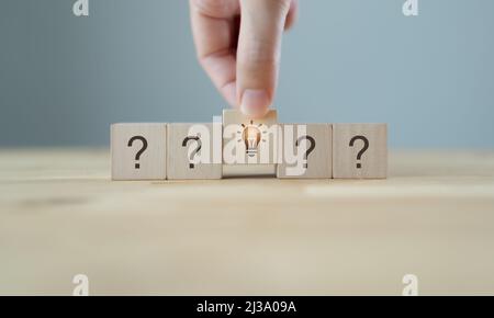 Kreative Idee, Innovation und Lösungskonzept. Team-Brainstorming zur Problemlösung. Hand setzt Holzwürfel mit Glühbirne Symbol stehen mit ques Stockfoto