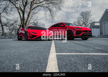 Eine schöne Aufnahme von zwei roten Lamborghini Autos Urus und Huracan geparkt auf der Straße tagsüber gegen bewölkten Himmel in Boston, USA Stockfoto