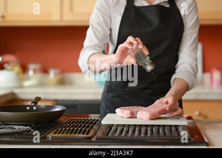 Der Küchenchef bereitet frische Schweinefleisch Steaks in der Küche, Hausmannskost-Menü. Kulinarische Rezepte. Restaurant-Menü. Stockfoto