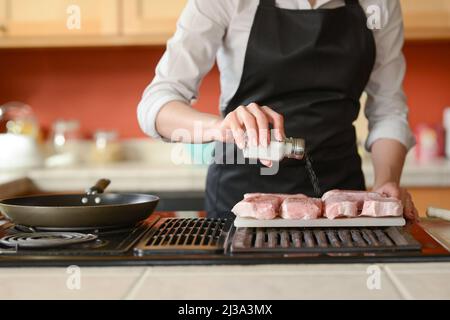 Der Küchenchef bereitet frische Schweinefleisch Steaks in der Küche, Hausmannskost-Menü. Kulinarische Rezepte. Restaurant-Menü. Stockfoto