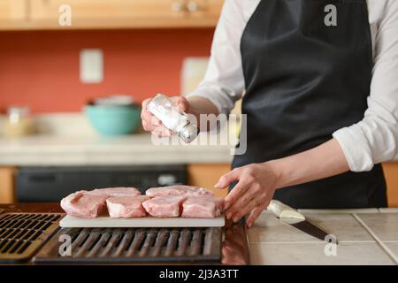 Der Küchenchef bereitet frische Schweinefleisch Steaks in der Küche, Hausmannskost-Menü. Kulinarische Rezepte. Restaurant-Menü. Stockfoto