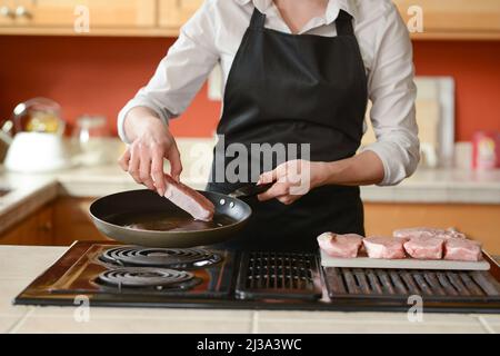 Der Küchenchef bereitet frische Schweinefleisch Steaks in der Küche, Hausmannskost-Menü. Kulinarische Rezepte. Restaurant-Menü. Stockfoto