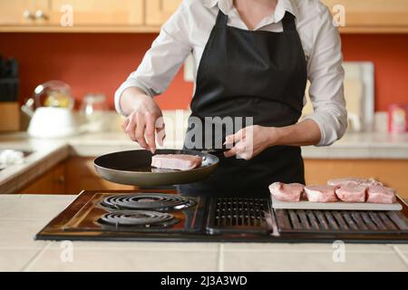 Der Küchenchef bereitet frische Schweinefleisch Steaks in der Küche, Hausmannskost-Menü. Kulinarische Rezepte. Restaurant-Menü. Leckeres Essen Stockfoto