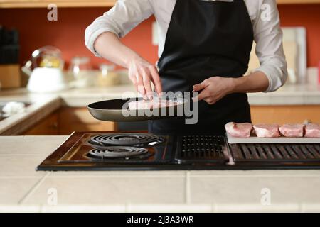 Der Küchenchef bereitet frische Schweinefleisch Steaks in der Küche, Hausmannskost-Menü. Kulinarische Rezepte. Restaurant-Menü. Stockfoto