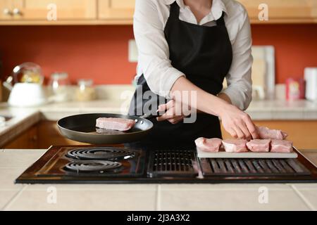 Der Küchenchef bereitet frische Schweinefleisch Steaks in der Küche, Hausmannskost-Menü. Kulinarische Rezepte. Restaurant-Menü. Stockfoto