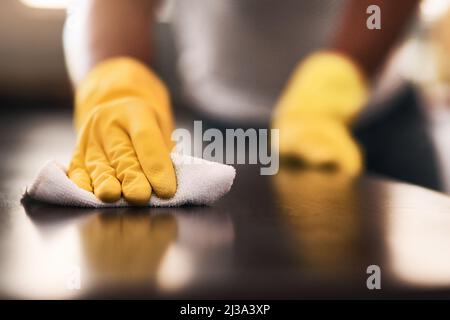 Ein keimfreies Zuhause zu halten. Eine kurze Aufnahme eines unkenntlichen Mannes, der zu Hause eine Küchentheke putzt. Stockfoto