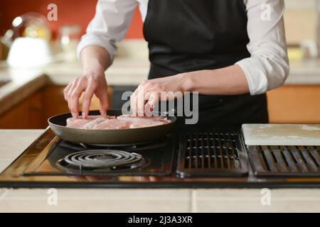 Der Küchenchef bereitet frische Schweinefleisch Steaks in der Küche, Hausmannskost-Menü. Kulinarische Rezepte. Restaurant-Menü. Stockfoto