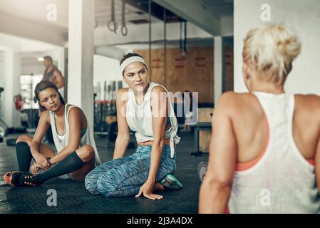 Neue Freunde im Fitnessstudio finden. Aufnahme einer Gruppe junger Frauen, die nach einem Training im Fitnessstudio eine Pause machen. Stockfoto