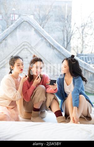Schöne junge modische chinesische Damen versuchen Lippenstift in ihrer Freizeit - Stock Foto Stockfoto