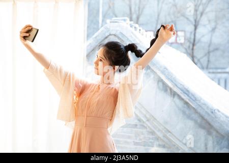 Eine junge modische Frau verbringt ihre Freizeit damit, sich selbst im Spiegel mit ihrer Selfie-Funktion für Mobiltelefone zu betrachten – Stockfoto Stockfoto