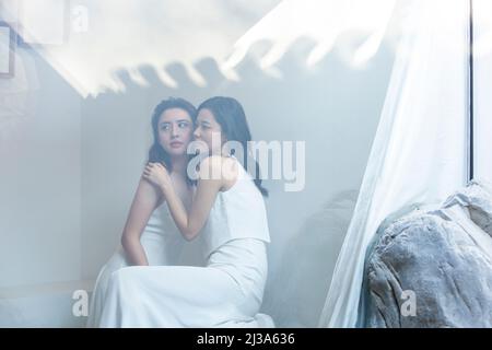Kreative Bilder von modischen weiblichen Models mit wunderschönen Kleidern und zarten Make-up stehen im Fenster von Luxusgütern - Stock Foto Stockfoto