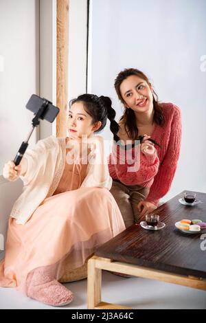 Modische junge chinesische Frauen, die zur Teezeit ein Selfie mit einem Selfie-Stick machen - Stockfoto Stockfoto